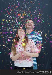 handsome young couple celebrating new year and chrismas party while blowing confetti decorations to camera isolated over gray background