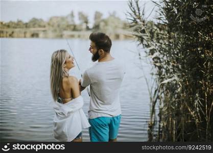 Handsome young couple enjoying fishing on lake at sunny summer day