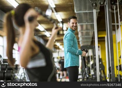 Handsome young couple exercise bodybuilding exercises in the modern gym