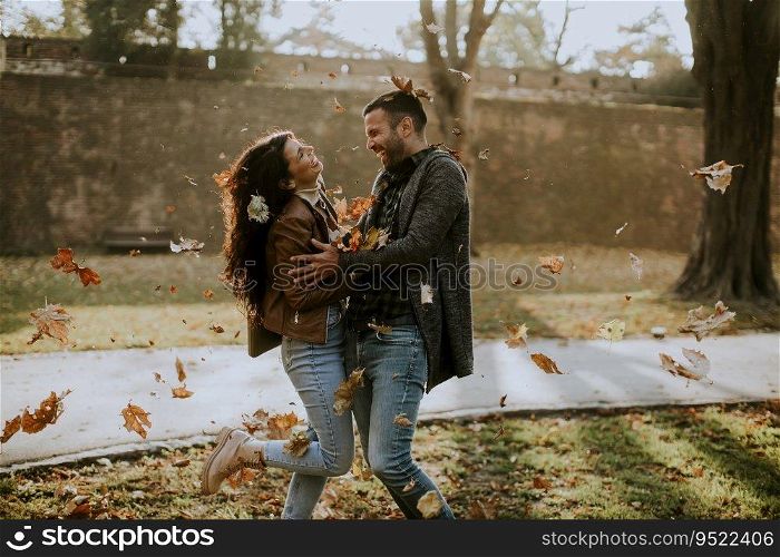Handsome young couple having fun with leaves in autumn park