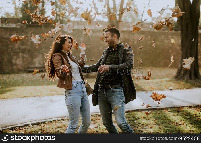 Handsome young couple having fun with leaves in autumn park