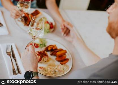 Handsome young couple having lunch with white wine in the restaurant