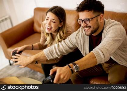 Handsome young couple playing video games at home, sitting on sofa and enjoying themselves