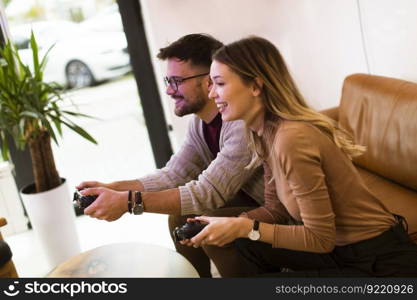 Handsome young couple playing video games at home, sitting on sofa and enjoying themselves