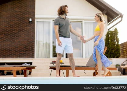 Handsome young couple relaxing by the swimming pool in the house backyard