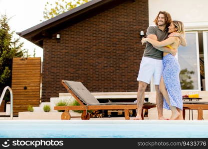 Handsome young couple relaxing by the swimming pool in the house backyard