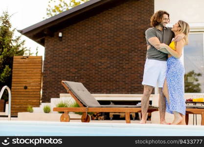 Handsome young couple relaxing by the swimming pool in the house backyard