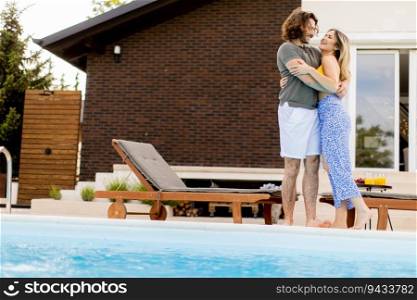 Handsome young couple relaxing by the swimming pool in the house backyard