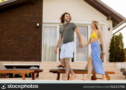 Handsome young couple relaxing by the swimming pool in the house backyard