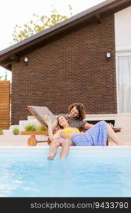 Handsome young couple relaxing by the swimming pool in the house backyard