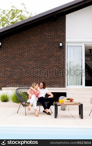 Handsome young couple relaxing by the swimming pool in the house backyard