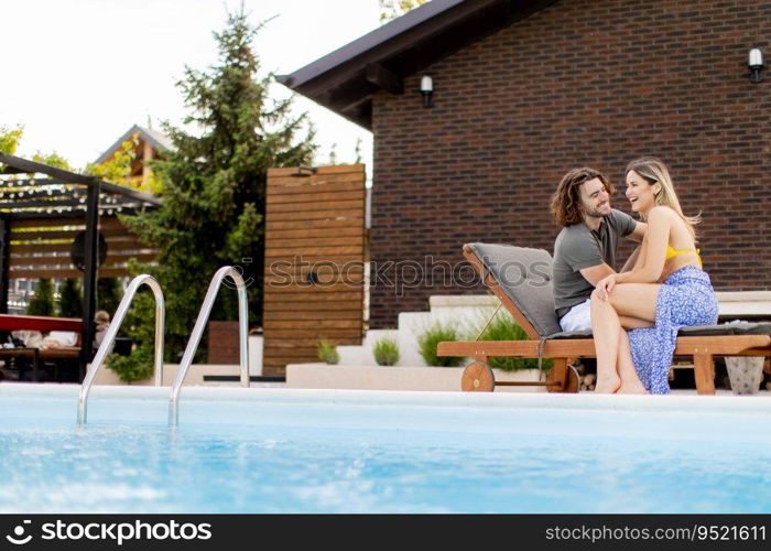 Handsome young couple relaxing by the swimming pool in the house backyard