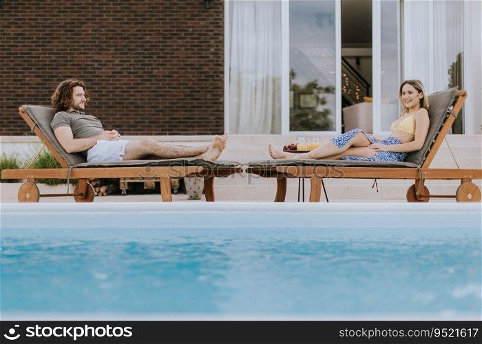 Handsome young couple relaxing by the swimming pool in the house backyard