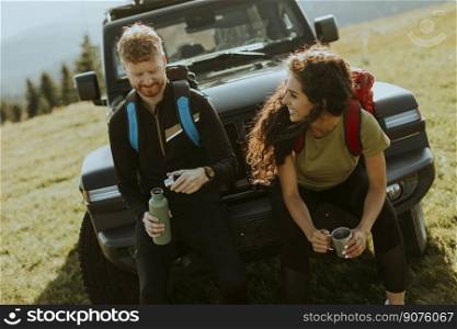 Handsome young couple relaxing on a terrain vehicle hood at countryside