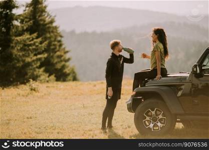 Handsome young couple relaxing on a terrain vehicle hood at countryside