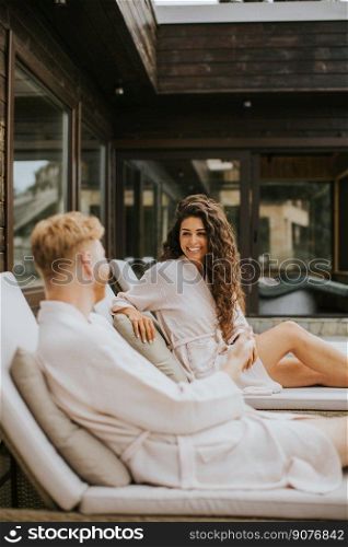 Handsome young couple relaxing on beds on the outdoor terrace