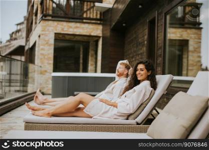 Handsome young couple relaxing on beds on the outdoor terrace
