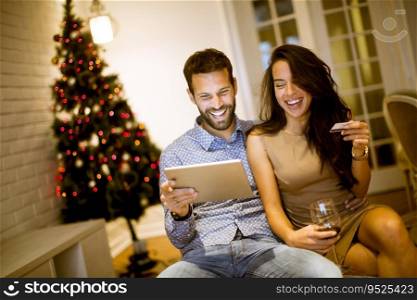 Handsome young couple shopping with tablet at New Years eve at home
