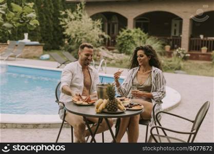 Handsome young couple sitting in the backyard, drinking lemande and eating fresh fruits