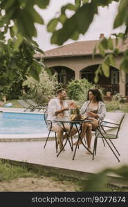 Handsome young couple sitting in the backyard, drinking lemande and eating fresh fruits