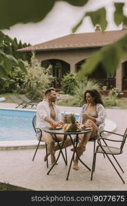 Handsome young couple sitting in the backyard, drinking lemande and eating fresh fruits