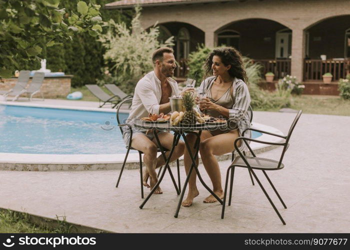 Handsome young couple sitting in the backyard, drinking lemande and eating fresh fruits