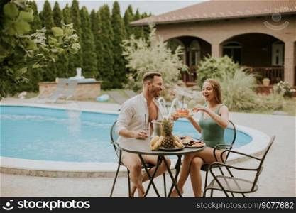 Handsome young couple sitting in the backyard, drinking lemande and eating fresh fruits