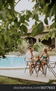 Handsome young couple sitting in the backyard, drinking lemande and eating fresh fruits