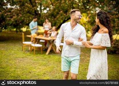 Handsome young couple walking in the garden in front of their friends