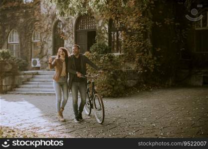Handsome young couple walking with bicycle in autumn park
