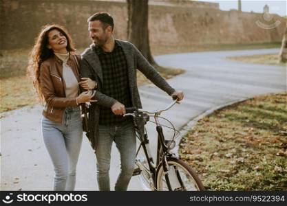 Handsome young couple walking with bicycle in autumn park