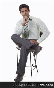 Handsome young executive sitting on chair and looking away