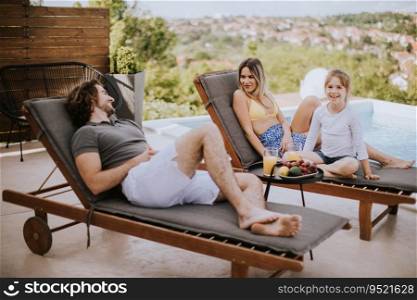 Handsome young family relaxing by the swimming pool in the house backyard