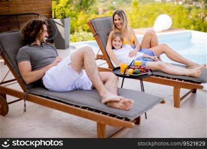 Handsome young family relaxing by the swimming pool in the house backyard
