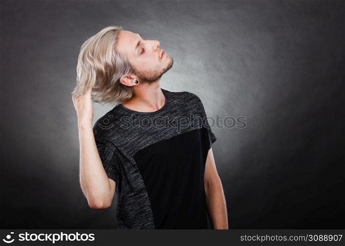 Handsome young fashion model with colored hair highlighted stylish haircut, ear plug, side view. Portrait young man with stylish haircut