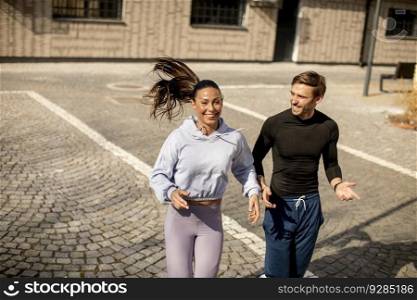 Handsome young fitness couple running in urban area