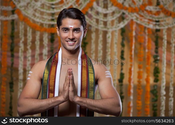 Handsome young groom standing with flower decoration in background
