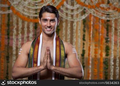 Handsome young groom standing with flower decoration in background