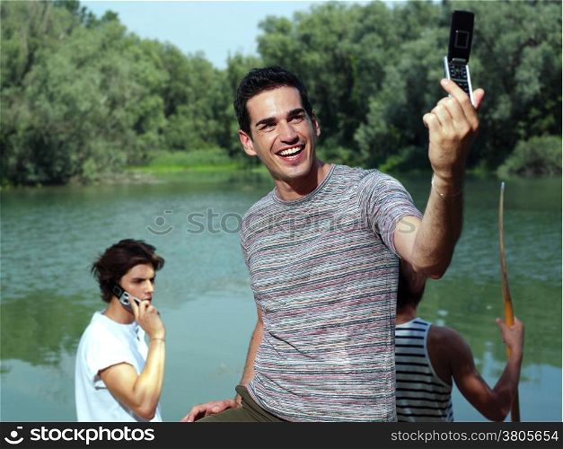 Handsome young guy taking photo with cellphone in park - Outdoor