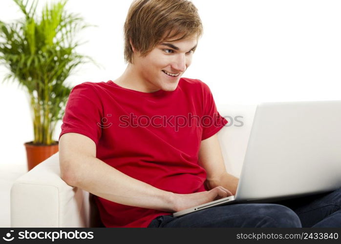 Handsome young man at home sitting on the couch and working on the laptop