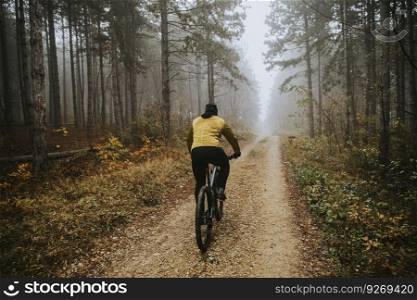 Handsome young man biking through autumn forest