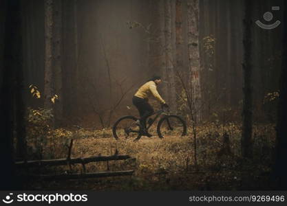 Handsome young man biking through autumn forest