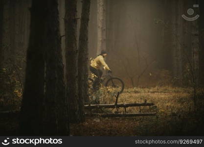 Handsome young man biking through autumn forest