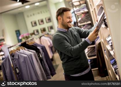 Handsome young man buying clothes in the store