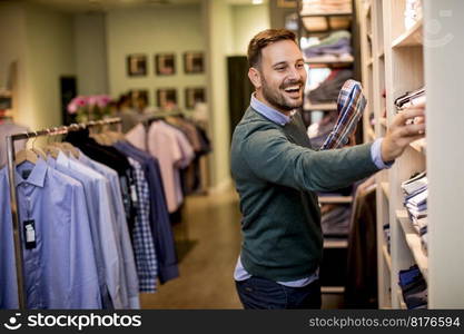 Handsome young man buying shirt in the store