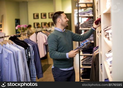 Handsome young man buying shirt in the store