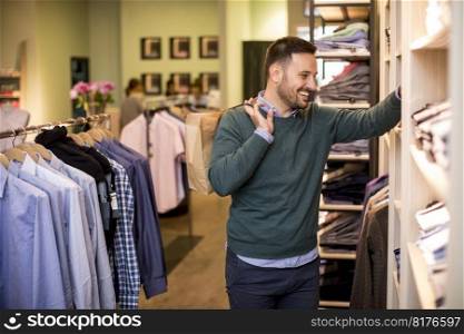 Handsome young man buying shirt in the store