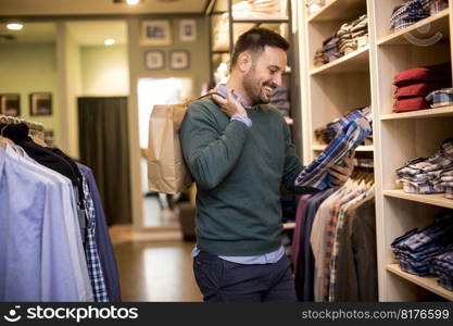 Handsome young man buying shirt in the store