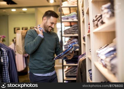 Handsome young man buying shirt in the store