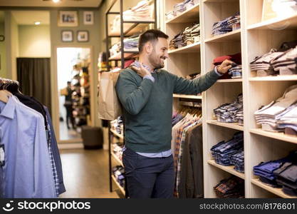 Handsome young man buying shirt in the store